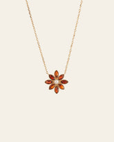 The CAMELLIA Cámellia Garnet Pearl Necklace is a 14K Yellow Gold Vermeil piece featuring a flower-shaped pendant with a white central stone, elegantly encircled by vibrant orange stones.