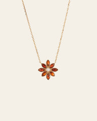 The CAMELLIA Cámellia Garnet Pearl Necklace is a 14K Yellow Gold Vermeil piece featuring a flower-shaped pendant with a white central stone, elegantly encircled by vibrant orange stones.