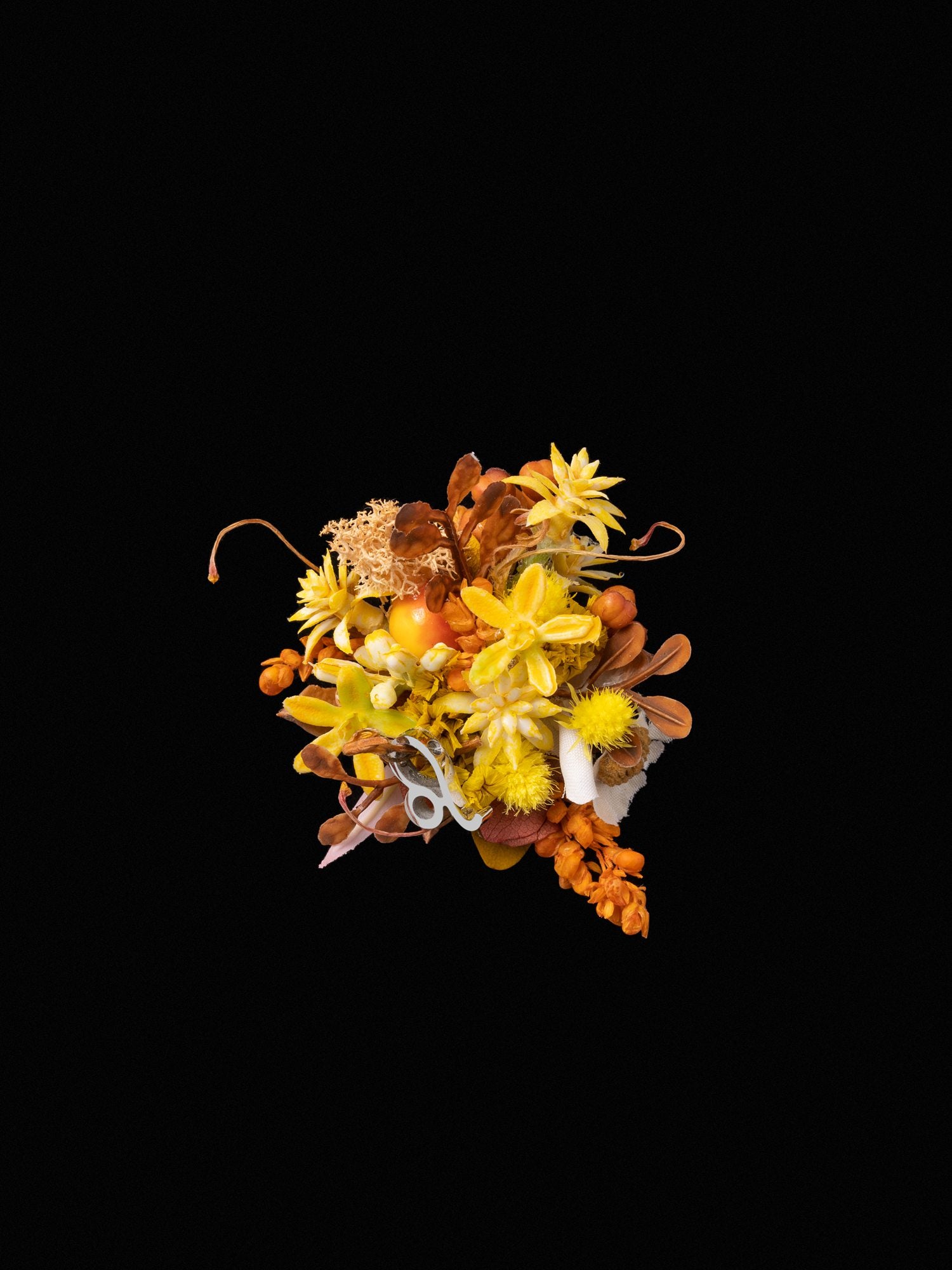 Set against a black background, the Leo Flower Ring by CAMELLIA features a delicate arrangement of yellow and orange flowers with dried elements, capturing nature's artistry and reminiscent of a custom symbol flower ring handcrafted in New York.