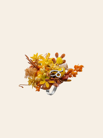 The Leo Flower Ring by CAMELLIA is a custom symbol ring with yellow and orange flowers on a light beige background, handcrafted in New York. The Leo Flower Ring by CAMELLIA is a custom symbol ring with yellow and orange flowers on a light beige background, handcrafted in New York.