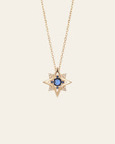 The New York Sapphire Pentagram Necklace by CAMELLIA features a star-shaped pendant with a central sapphire encircled by small clear stones, set on a plain background.