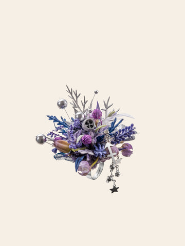 The CAMELLIA Sagittarius Flower Ring features a detailed purple and silver floral arrangement accented with a star charm, metallic balls, and sprigs, beautifully set against a plain cream background. The CAMELLIA Sagittarius Flower Ring features a detailed purple and silver floral arrangement accented with a star charm, metallic balls, and sprigs, beautifully set against a plain cream background.