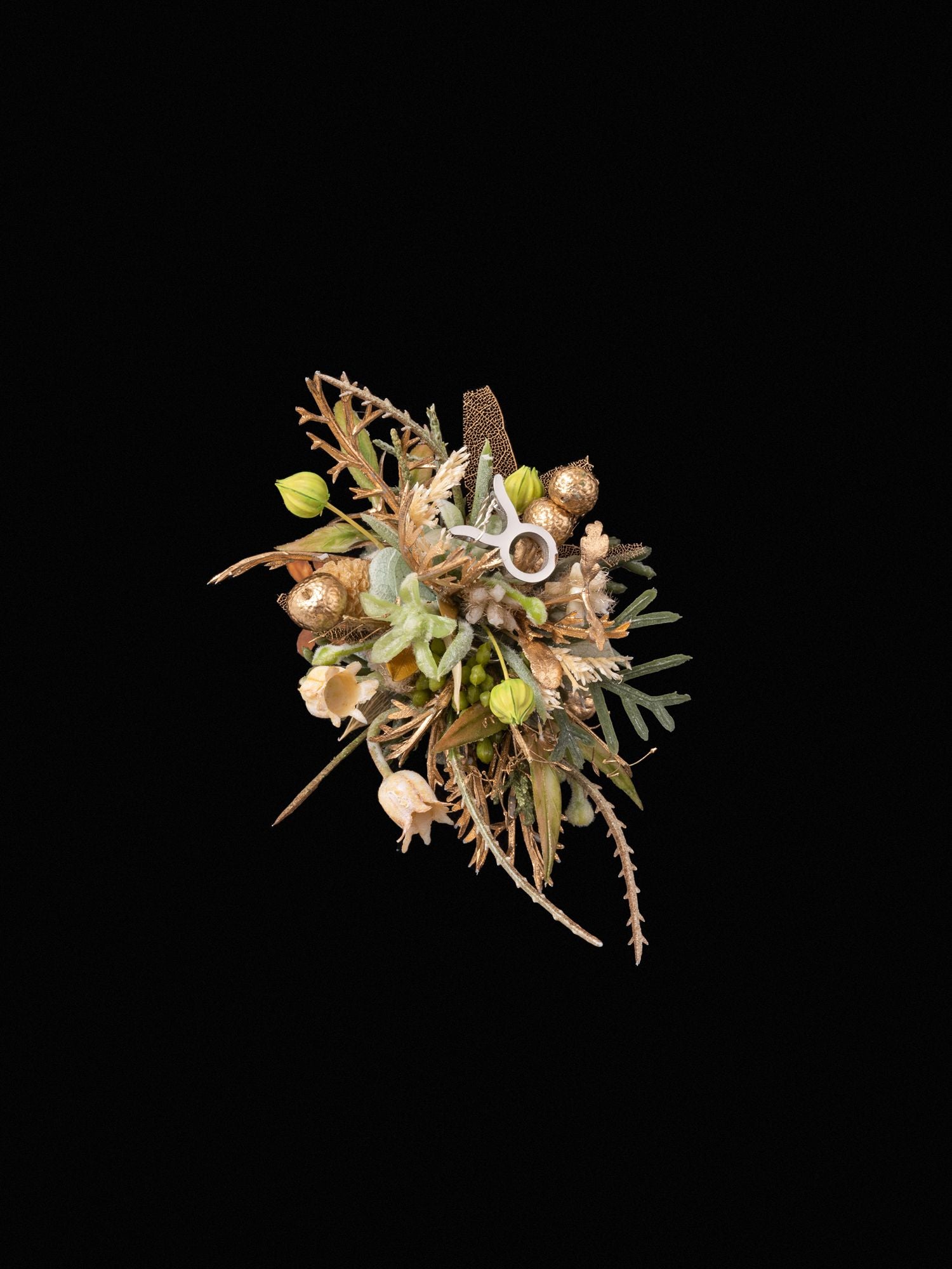 The Taurus Flower Ring by CAMELLIA showcases an intricate bouquet with green leaves, beige flowers, and gold accents on a black background, mirroring the elegance and artistry of a handcrafted design.