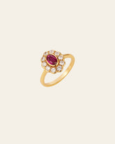 Introducing the TiAmo Oval Ruby Ring by CAMELLIA: a stunning gold piece with an oval red gemstone encircled by clear stones in a halo setting, exuding vintage jewelry charm. Perfect for those seeking elegance and timeless sophistication.