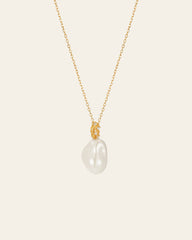 The Alyssa Barquoe Pearl Necklace by CAMELLIA features a gold chain with a single large, irregular white pearl pendant. With its 14K gold vermeil finish, it exudes timeless elegance and evokes French vintage design against a plain background.