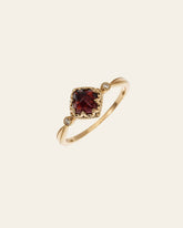 The CAMELLIA 14K Solid Gold Carena Garnet Ring features a vintage-inspired design with a cushion-cut red garnet set in an ornate bezel and delicate detailing along the band.