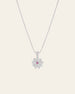 The Elsa Lotus Ruby Necklace by CAMELLIA is a sterling silver piece with a lotus pendant featuring a central pink gemstone. Handcrafted in New York, it embodies elegance and artistry against its plain light backdrop.