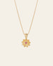 The Elsa Lotus Ruby Necklace by CAMELLIA is a handcrafted gold piece with a lotus-shaped pendant, featuring a small pink gemstone at the center, crafted in New York and displayed against a plain backdrop.
