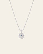The Elsa Peony Sapphire Necklace by CAMELLIA is a sterling silver accessory featuring a daisy-shaped pendant with a central blue gemstone set against a light background.