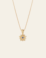 The Elsa Holly Tanzanite Necklace by CAMELLIA is a stunning 14K yellow gold vermeil piece with a star-shaped pendant and central blue gemstone, elegantly suspended on a fine chain. Hypoallergenic and perfect for any occasion, it ensures both style and comfort against your skin.