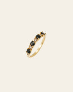 The Giselle Onyx Ring by CAMELLIA showcases alternating heart-shaped black onyx stones and small round clear stones in a stunning band pattern.