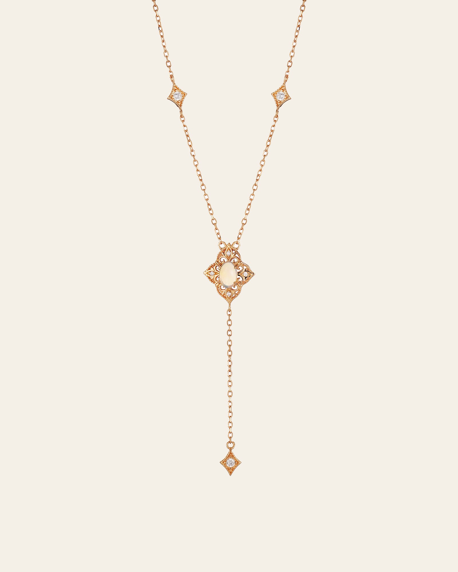 The Aurielle Opal Long Necklace by CAMELLIA is a hypoallergenic gold necklace featuring a central pearl pendant. It has a Y-shape design with diamond-shaped accents and small gems, ending in an elegantly long dangling chain.
