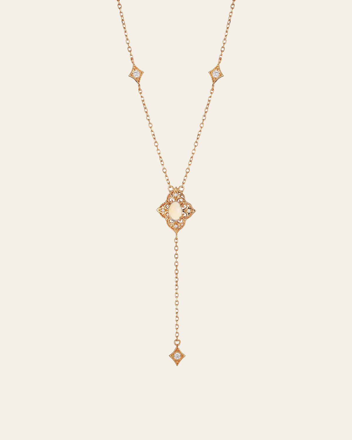 The Aurielle Opal Long Necklace by CAMELLIA is a hypoallergenic gold necklace featuring a central pearl pendant. It has a Y-shape design with diamond-shaped accents and small gems, ending in an elegantly long dangling chain.