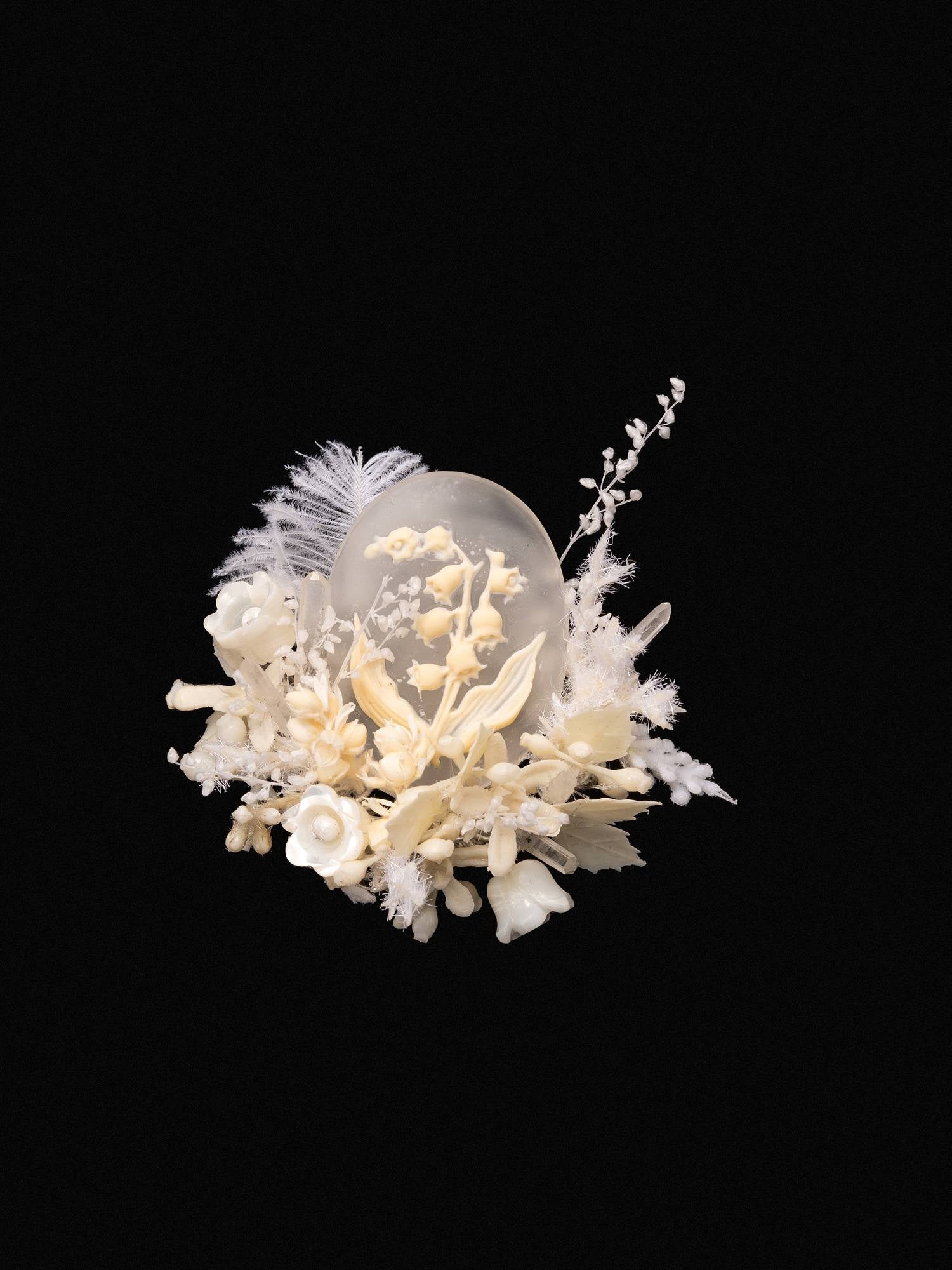 The CAMELLIA "Lily of the Valley Birth Flower Ring" is a delicate composition of white flowers and foliage encircling a translucent crystal sphere, set against a black background, reminiscent of something handcrafted in New York.