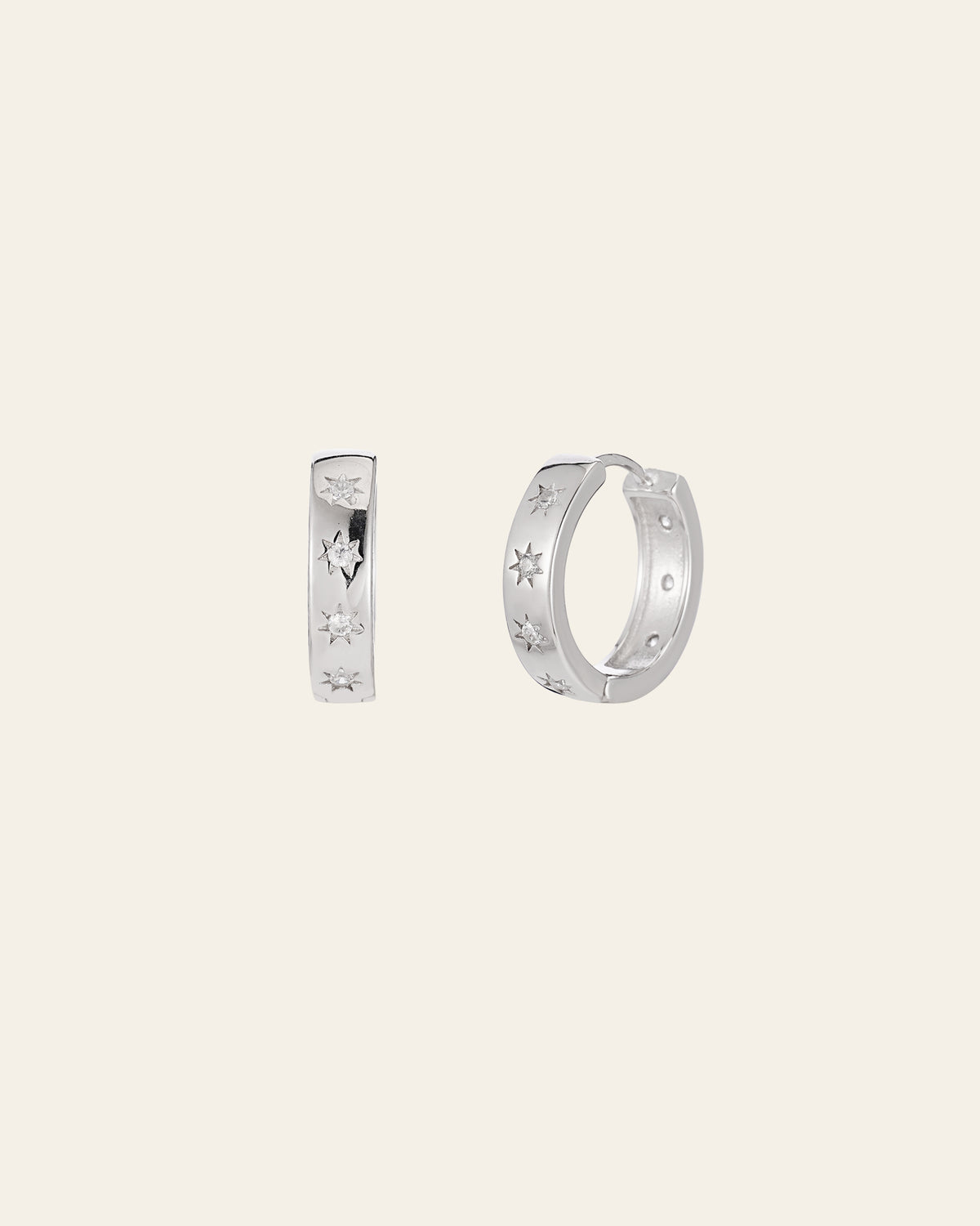 The Starburst Cz Hoops by CAMELLIA are sterling silver hoop earrings featuring star engravings on a light background, designed for ultimate hypoallergenic comfort.