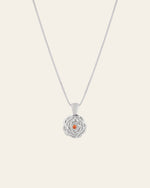 The Elsa Carnation Garnet Necklace by CAMELLIA is a handcrafted sterling silver piece from New York, featuring a round floral pendant with a central orange gemstone, displayed on a plain background.