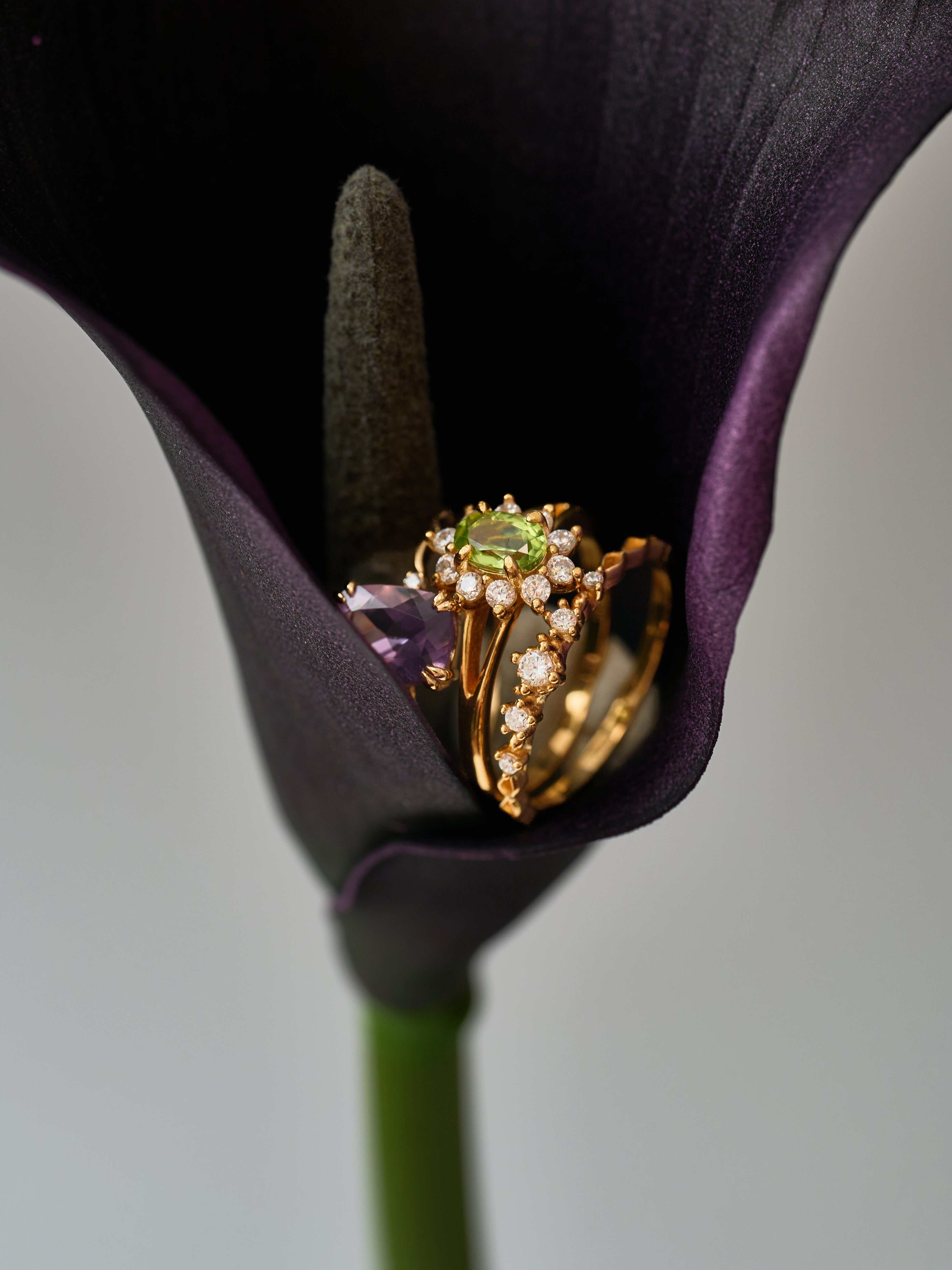 The CAMELLIA Lunar Amethyst Ring, crafted from gold and sterling silver with amethyst and diamonds, is handcrafted in New York and displayed inside a dark purple calla lily flower.