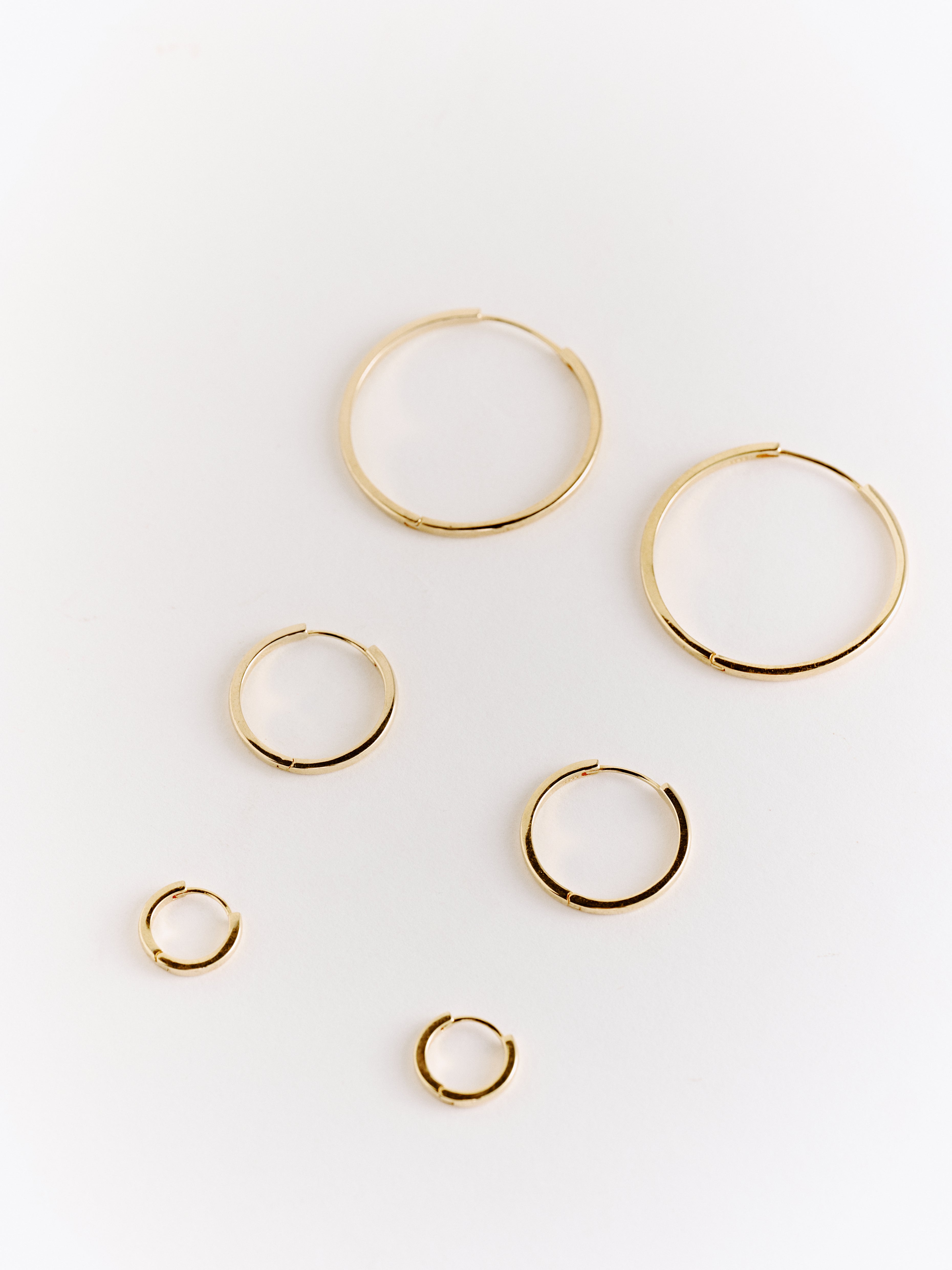Six handcrafted CAMELLIA 15mm Mother Hoops in 14K gold, displayed on a white background. These hypoallergenic earrings blend elegance and comfort, perfect for any style.