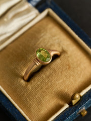 The CAMELLIA Eden Peridot Ring is a vintage-inspired gold vermeil piece with a central oval green peridot gemstone, presented in a cushioned ring box.