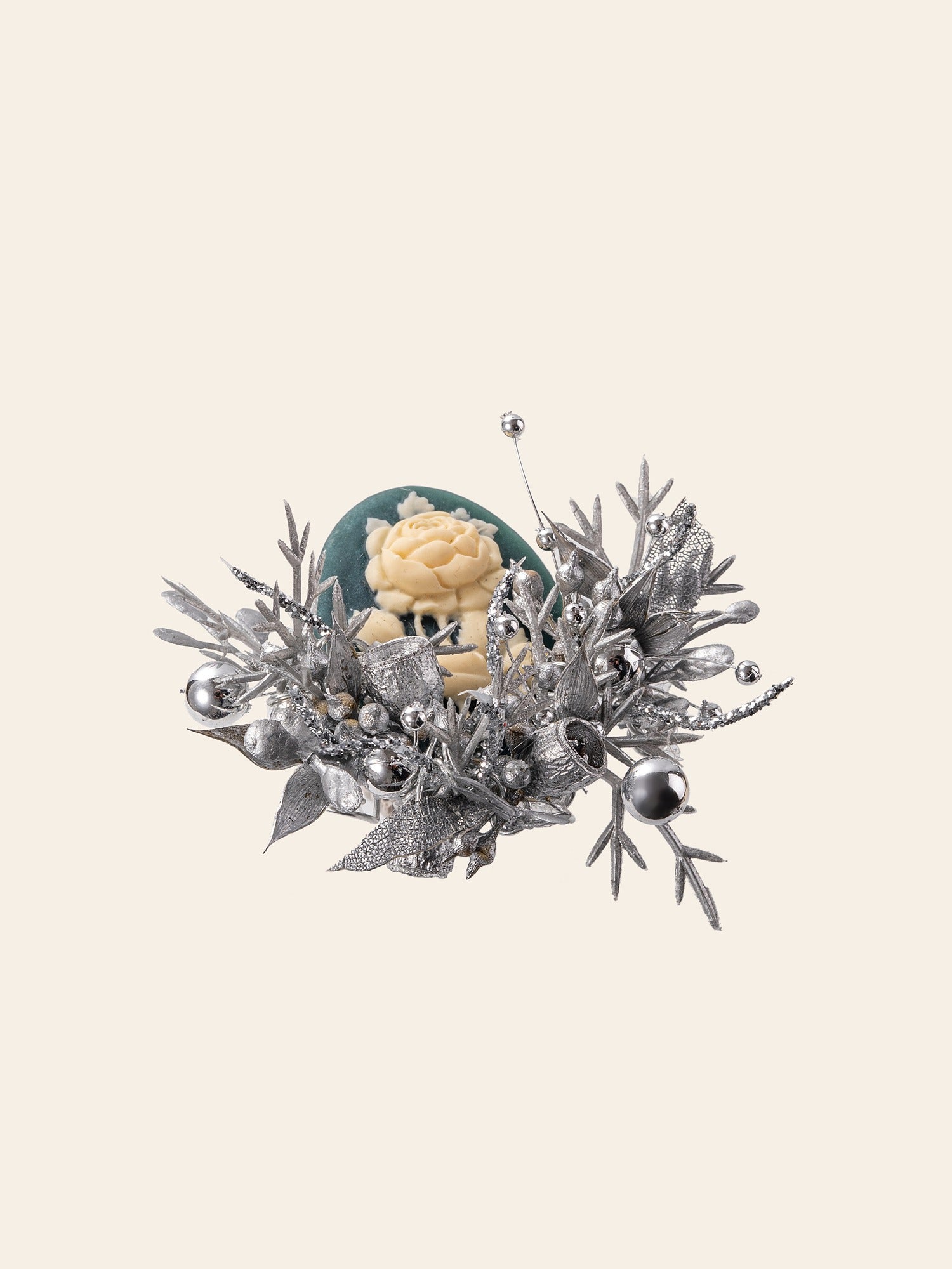 The CAMELLIA Cotton Rose Hibiscus Birth Flower Ring features a handcrafted silver floral arrangement with metallic leaves, berries, and branches surrounding a yellow rose on a teal backdrop, reminiscent of a custom symbol flower ring.
