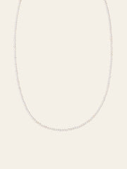 The CAMELLIA Classic Pearl Strand Necklace features small white freshwater pearls, elegantly displayed against a plain, light-colored background.