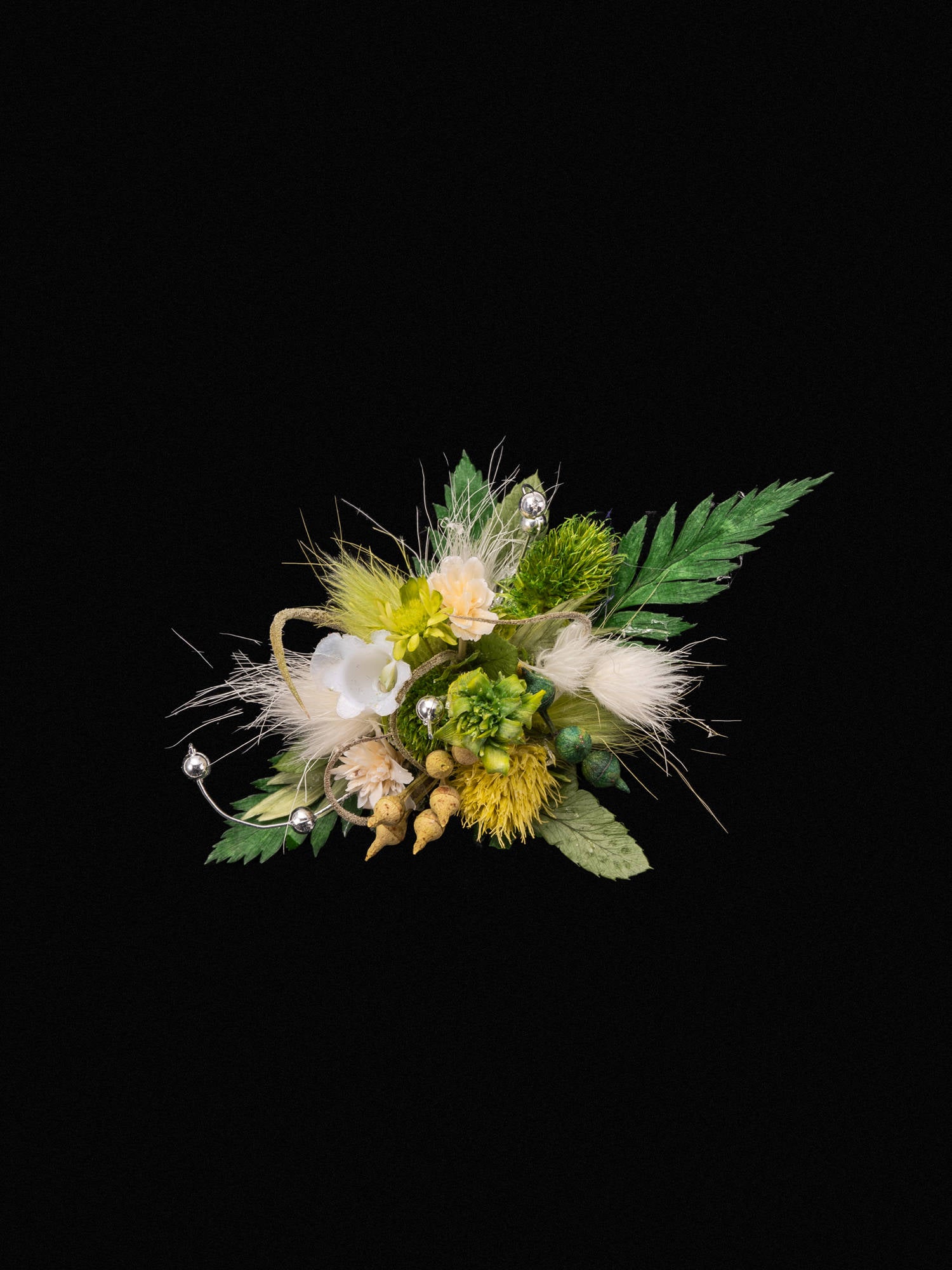 The CAMELLIA Verdant Dreams Flower Ring features a colorful floral design with green leaves, yellow and white flowers, berries, and wispy accents on a black backdrop, capturing the delicate charm of a handcrafted piece.