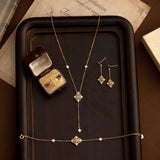 The CAMELLIA Aurielle Opal Jewelry Set, featuring a necklace, bracelet, earrings, and ring in a box, elegantly rests on a wooden tray. This hypoallergenic collection blends timeless design with exquisite gemstones for sensitive skin.