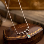 The CAMELLIA Starlight Opal Jewelry Set features a handcrafted sterling silver necklace with star-shaped links and an opal pendant, elegantly displayed on a closed brown leather box.