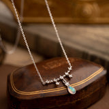 The CAMELLIA Starlight Opal Jewelry Set features a handcrafted sterling silver necklace with star-shaped links and an opal pendant, elegantly displayed on a closed brown leather box.