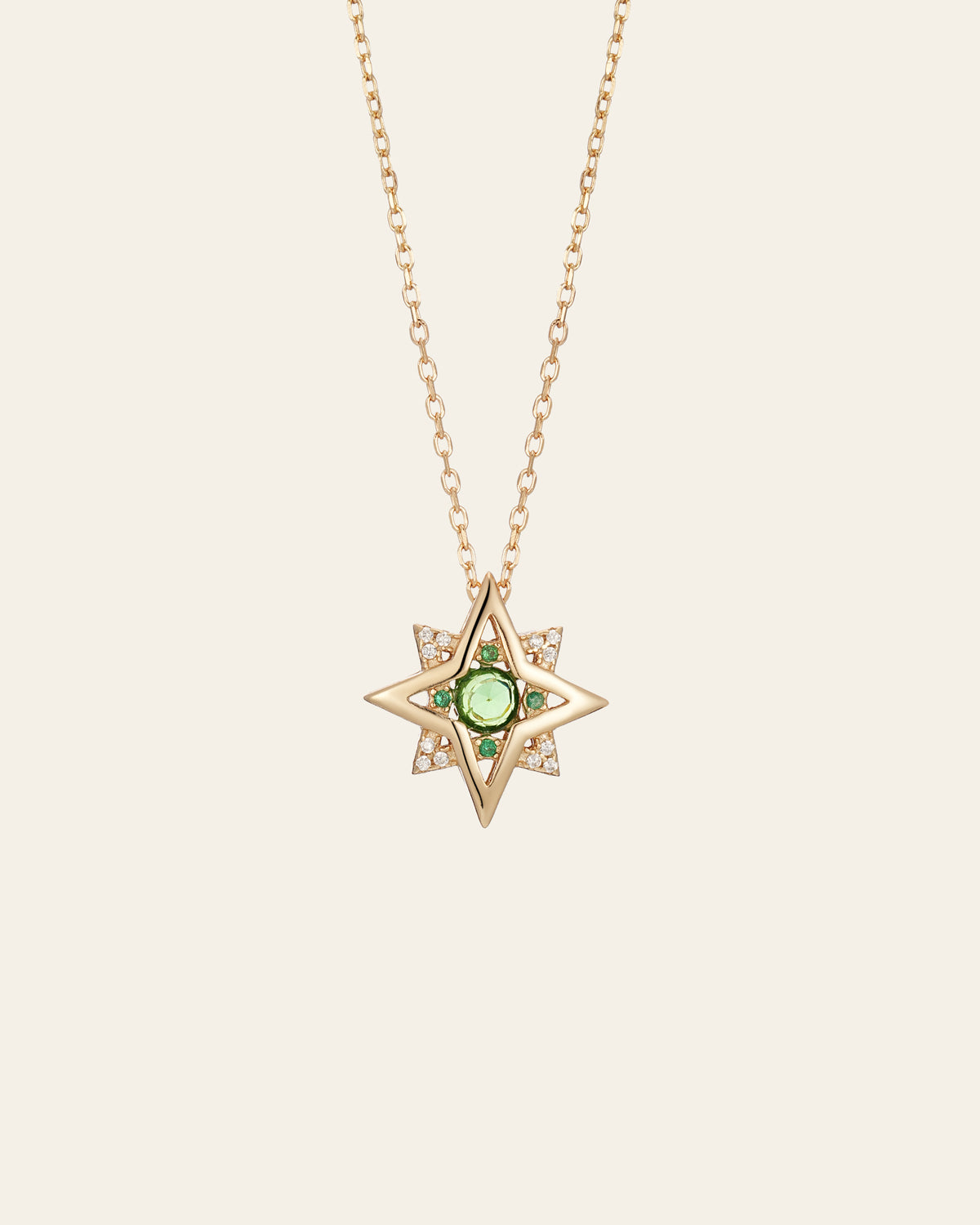The CAMELLIA New York Emerald Pentagram Necklace is a stunning gold star-shaped pendant on a thin chain, featuring a central emerald-like gem surrounded by tiny diamonds, crafted in luxurious 14K Yellow Gold Vermeil.