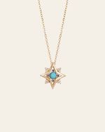 The New York Turquoise Pentagram Necklace by CAMELLIA is a handcrafted gold chain piece with a star-shaped pendant, central turquoise stone, and small clear stones at the tips.
