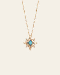 The New York Turquoise Pentagram Necklace by CAMELLIA is a handcrafted gold chain piece with a star-shaped pendant, central turquoise stone, and small clear stones at the tips.