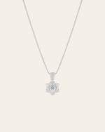 Introducing the Elsa Cherry Aquamarine Necklace by CAMELLIA: a meticulously handcrafted silver chain adorned with a flower-shaped pendant featuring a small aquamarine gem at its center.