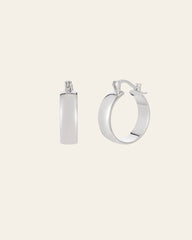 The CAMELLIA Eťa Hoops, made from sterling silver, shine elegantly against a light background. One hoop is shown side-on and the other front-facing, capturing the timeless allure of minimalist jewelry.