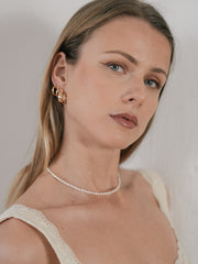 Close up: model wearing Camellia NYC Eta Hoops, which are delicate and glossy.